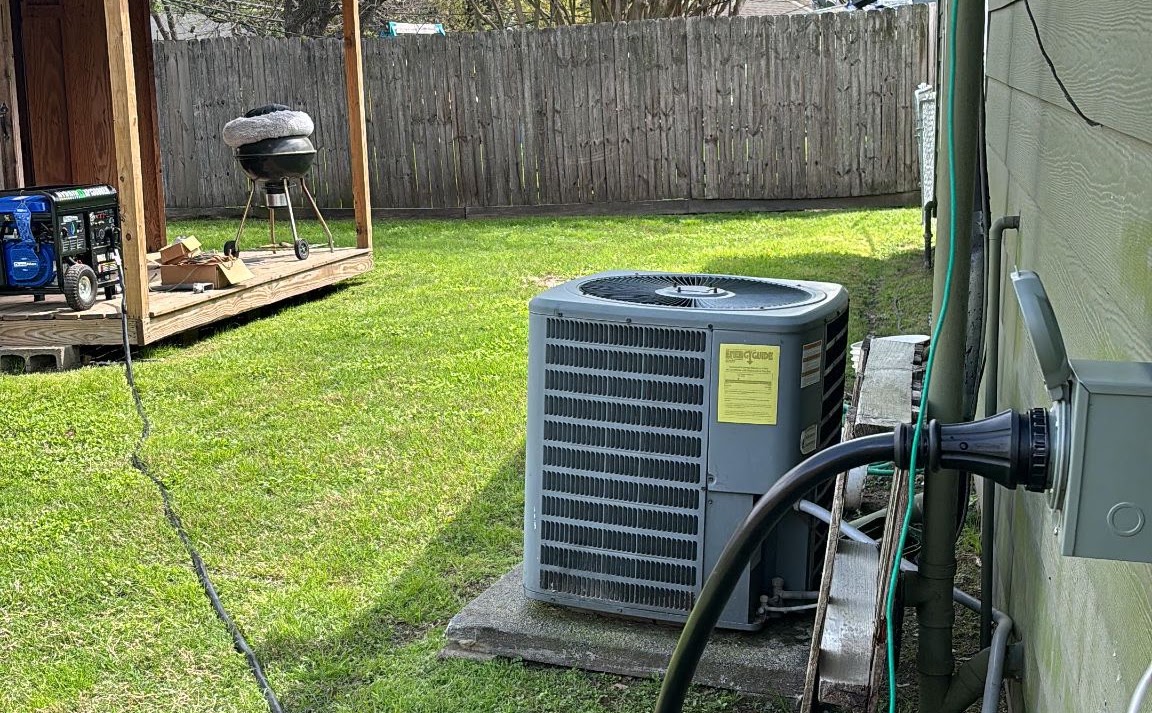 Generator cord connected to a house inlet, with the cord running across the yard toward a portable generator