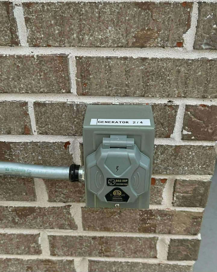 Gray generator power inlet installed on a brick wall with metal conduit
