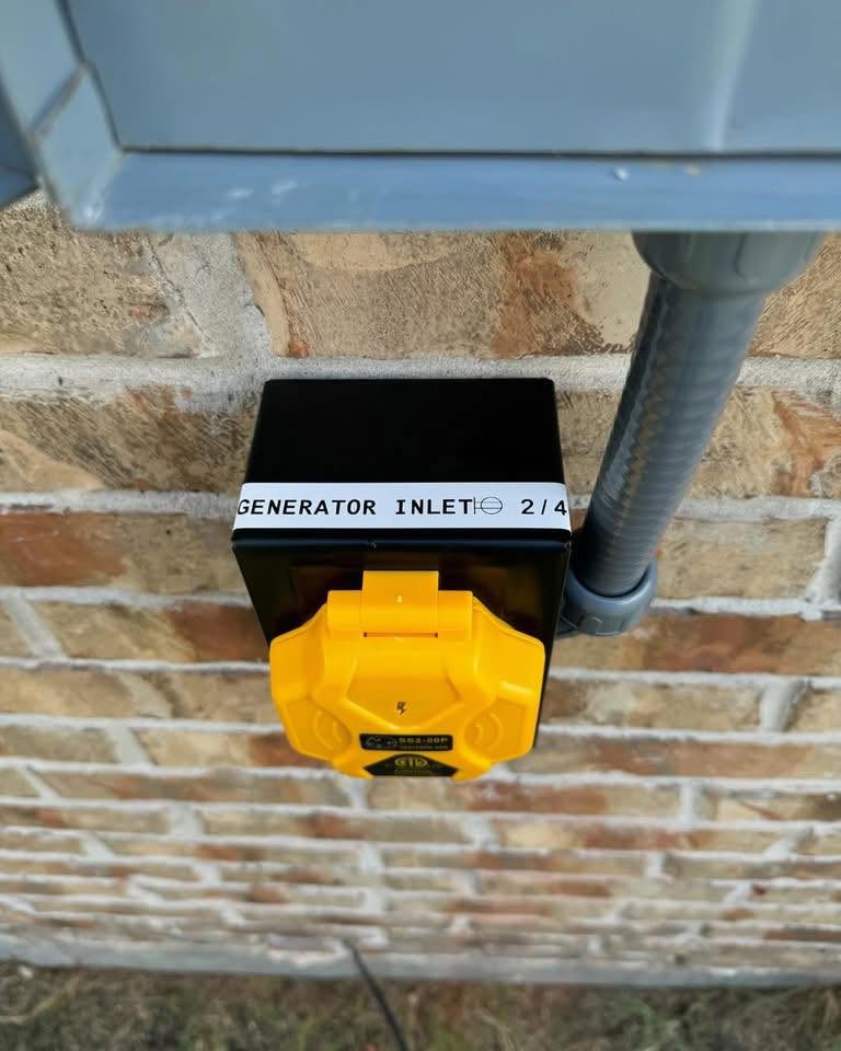 Generator inlet with a yellow weather cover beneath an electrical panel